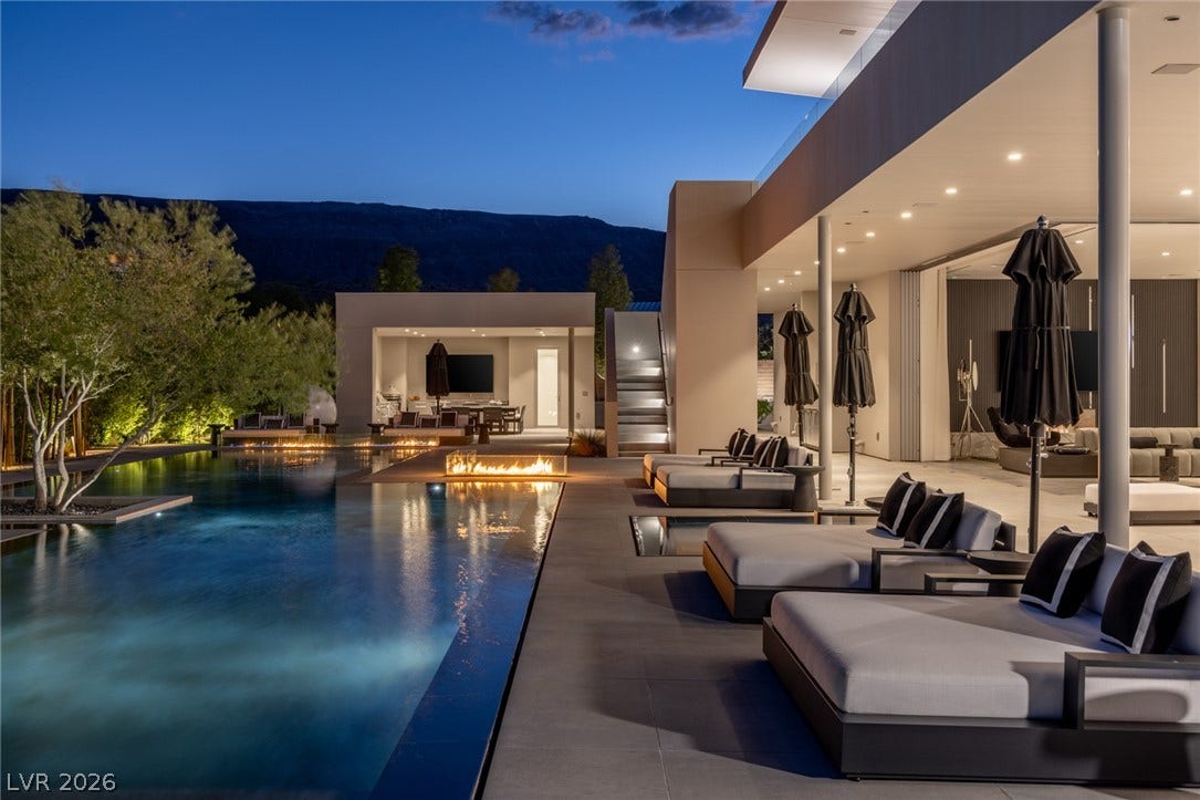 An inviting fire pit casts a warm glow over the tranquil pool and contemporary outdoor living area.