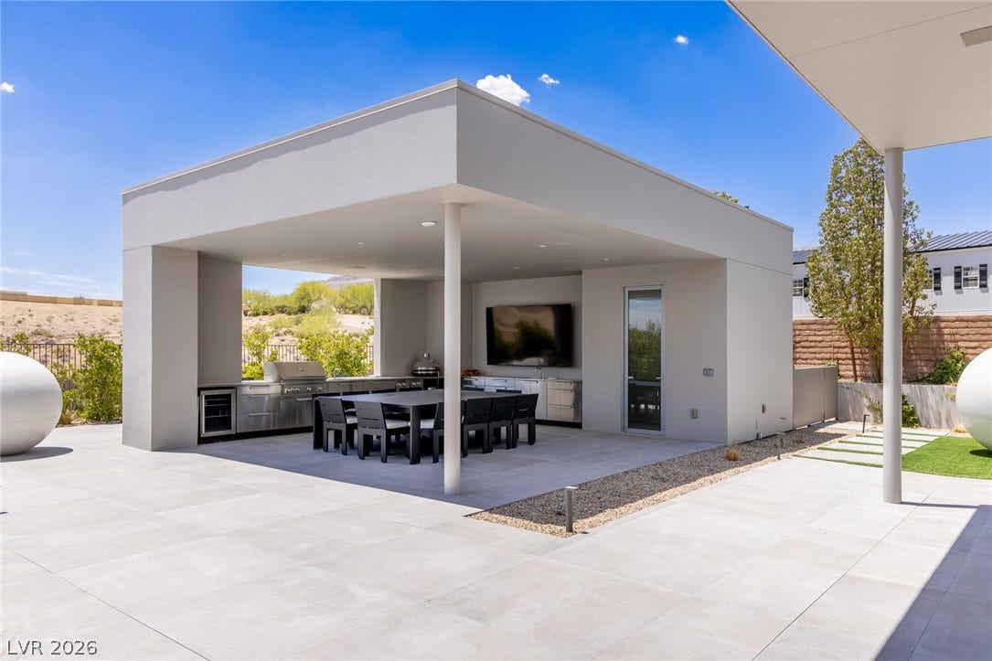 An inviting outdoor living space features an impressive kitchen and dining area for alfresco entertaining.