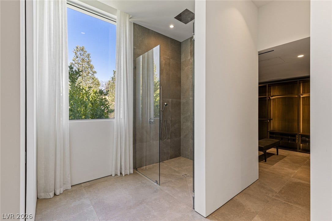 A well-lit, open-concept primary bathroom with a spacious walk-in shower and abundant natural light.