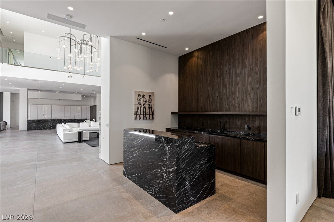 A sophisticated dry bar with marble countertops complements the spacious, open-concept living area.