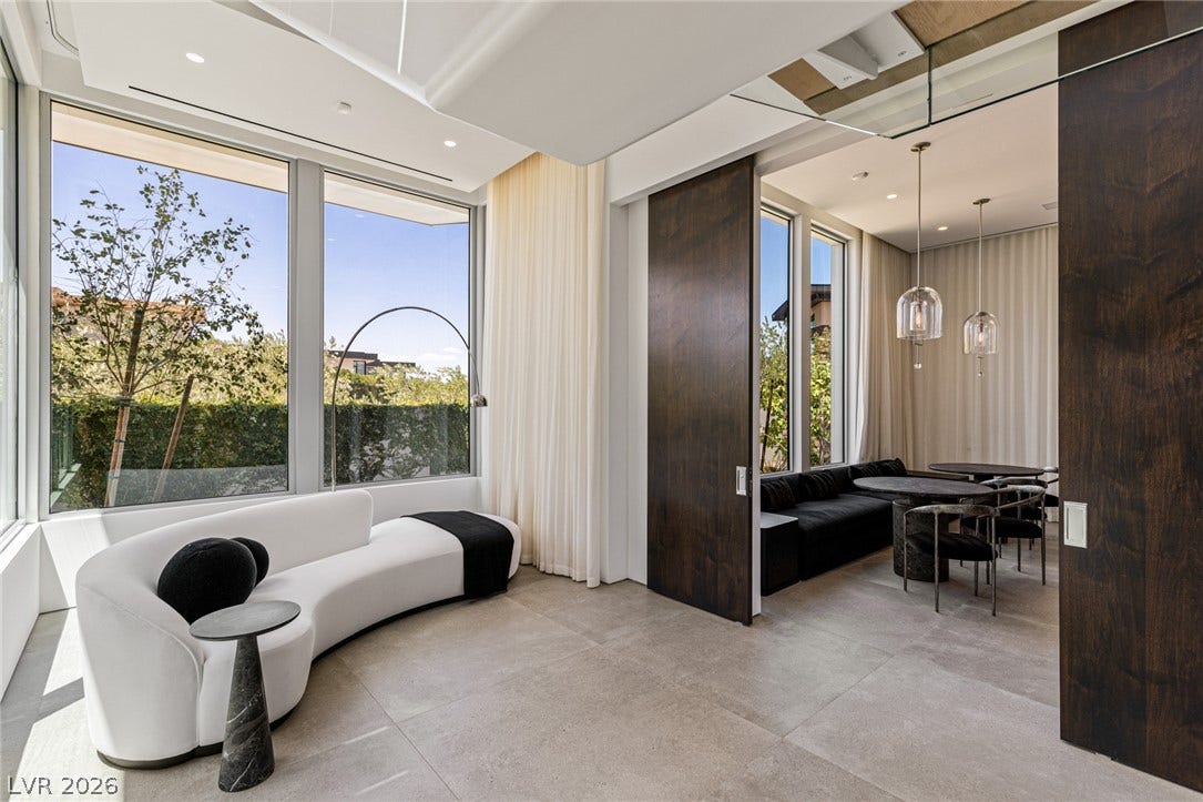Floor-to-ceiling windows illuminate a gracefully curved sofa, inviting relaxation in this versatile room.