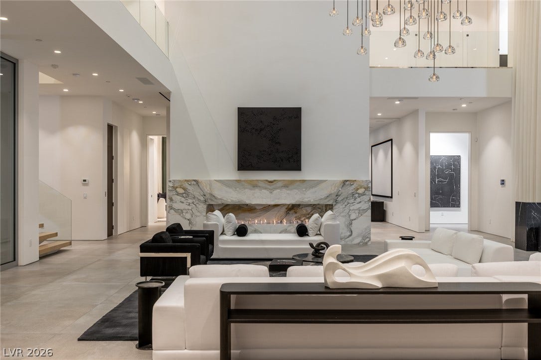 An inviting open floorplan awaits with a striking marble fireplace and high ceilings.