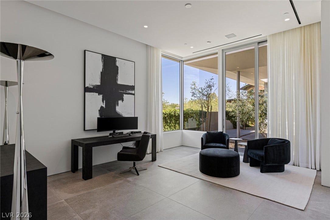 Floor-to-ceiling glass windows illuminate a versatile study, offering peaceful outdoor views.