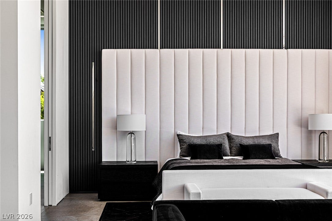 Luxurious bedroom retreat features sleek black paneled walls and a tall, plush upholstered headboard.