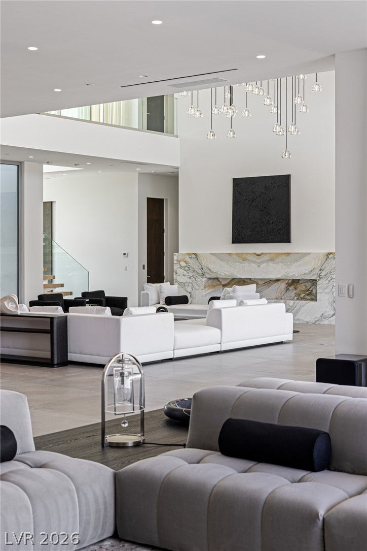 A grand living space features high ceilings and a striking marble fireplace, perfect for elegant gatherings.