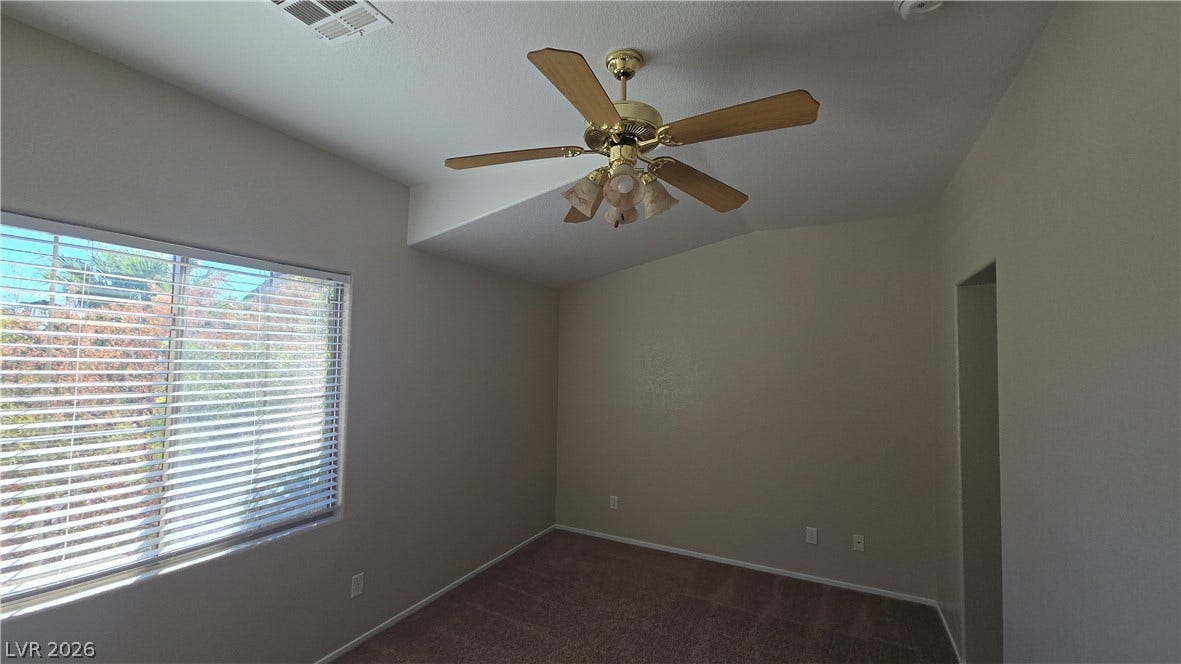 536 Civic Holiday Avenue, North Las Vegas, NV 89031 A spacious bedroom features neutral walls, plush carpeting, and a vaulted ceiling detail.