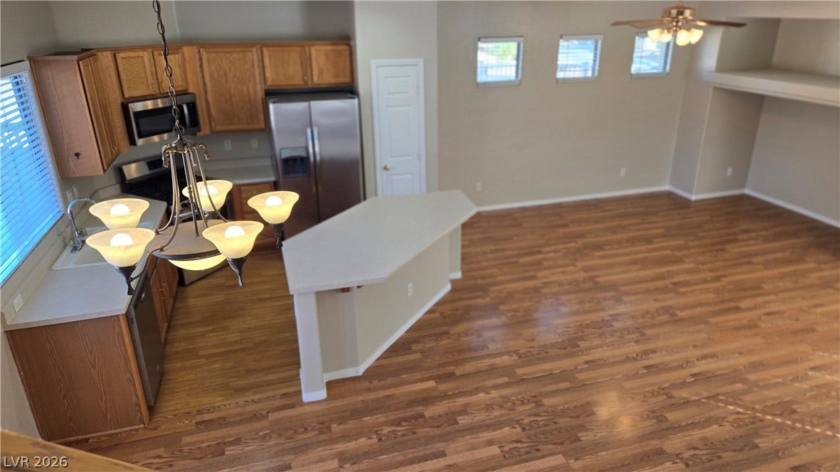 536 Civic Holiday Avenue, North Las Vegas, NV 89031 Rich wood flooring connects the open kitchen to a spacious living area under towering ceilings.