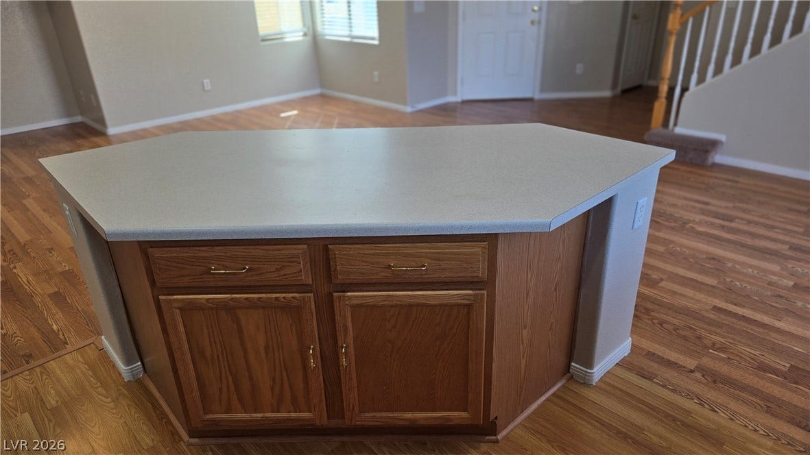 536 Civic Holiday Avenue, North Las Vegas, NV 89031 Warm wood flooring flows through an open-concept living area with a central kitchen island.