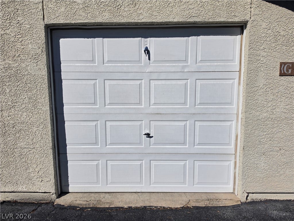8000 W Badura Avenue, #2111, Las Vegas, NV 89113 Textured stucco surrounds a classic paneled garage door set against a paved driveway.