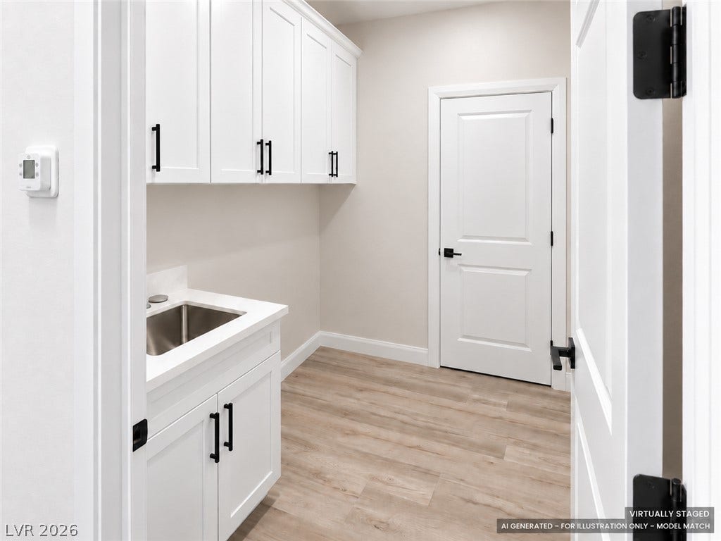 Virtually staged. A functional utility space highlights clean white cabinetry and durable wood-look flooring.