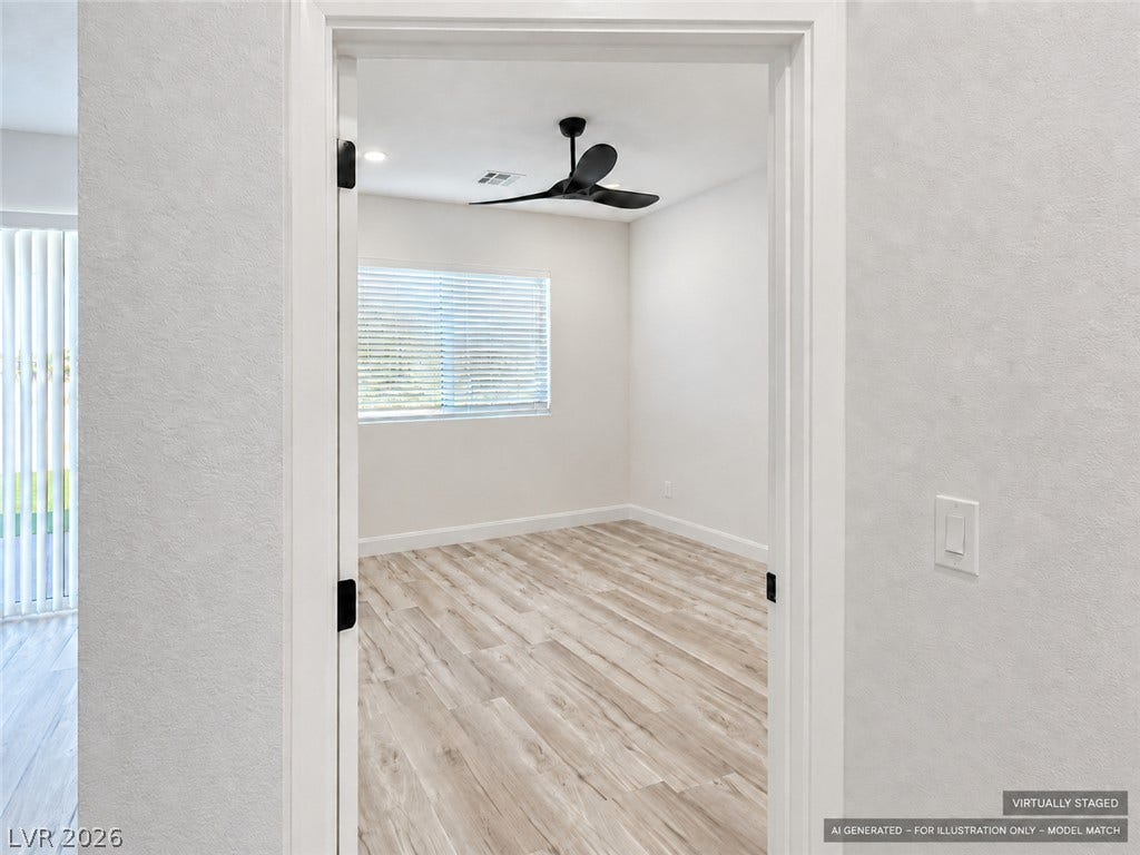 Virtually staged. Gleaming wood-look floors complement the light-filled bedroom visible through a classic doorway.