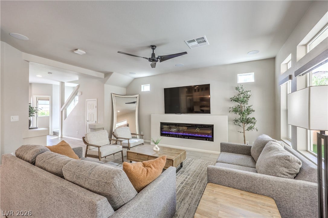 9267 Galen Glen Court, Las Vegas, NV 89139 An integrated electric fireplace centers this comfortable modern living area flanked by tall windows.