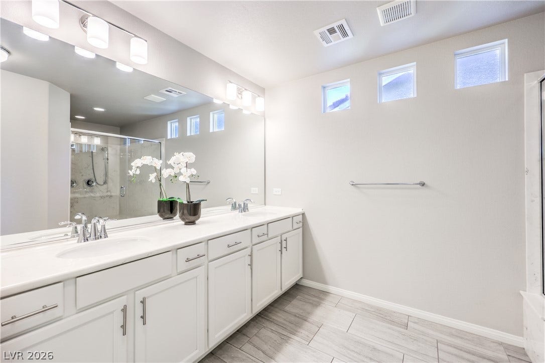 9267 Galen Glen Court, Las Vegas, NV 89139 High clerestory windows illuminate a dual-sink vanity and tiled floors in this primary bathroom.
