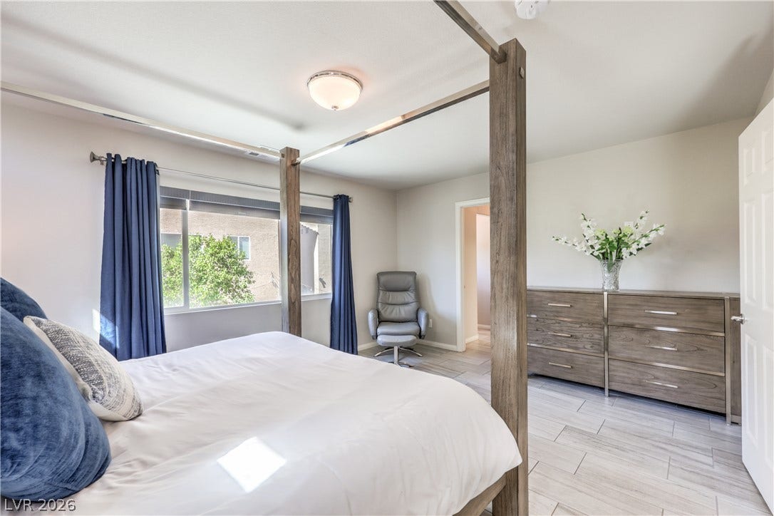 9267 Galen Glen Court, Las Vegas, NV 89139 A window frames garden views in a bedroom featuring light-toned flooring and neutral walls.