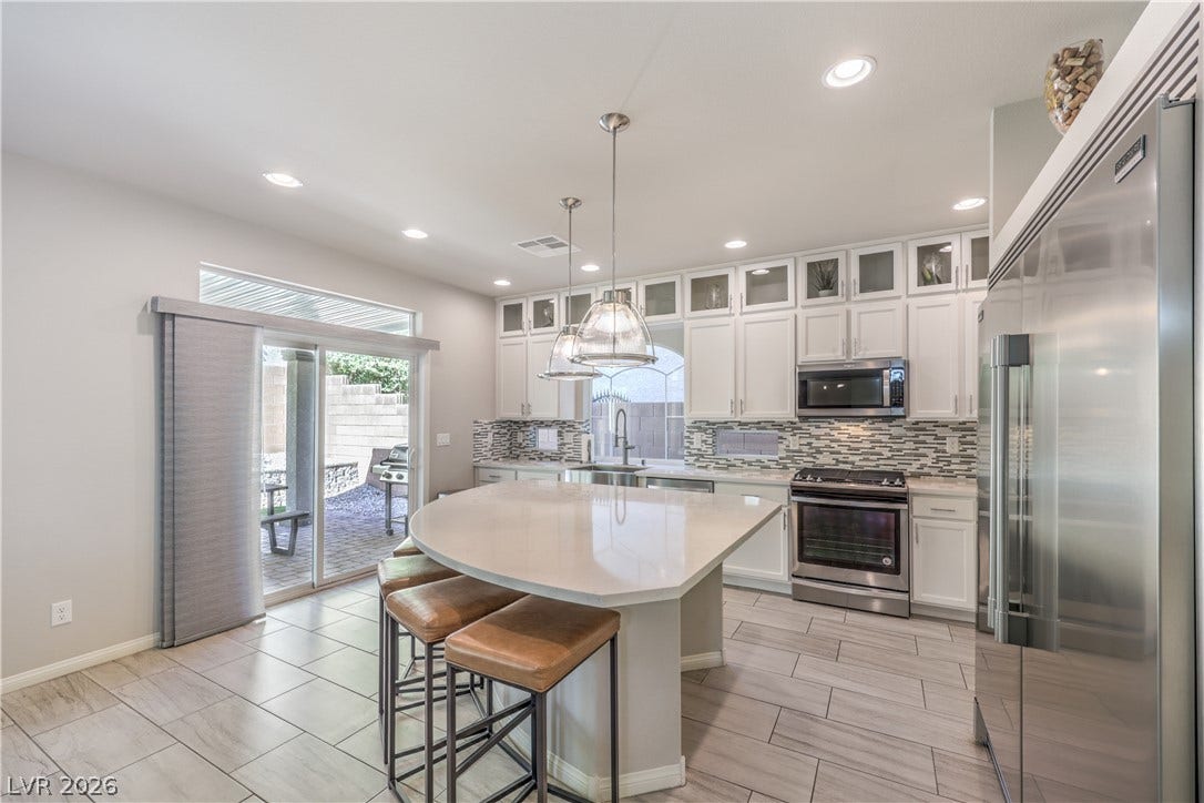 9267 Galen Glen Court, Las Vegas, NV 89139 Polished tile flooring and quartz countertops elevate this modern kitchen with sliding glass doors.