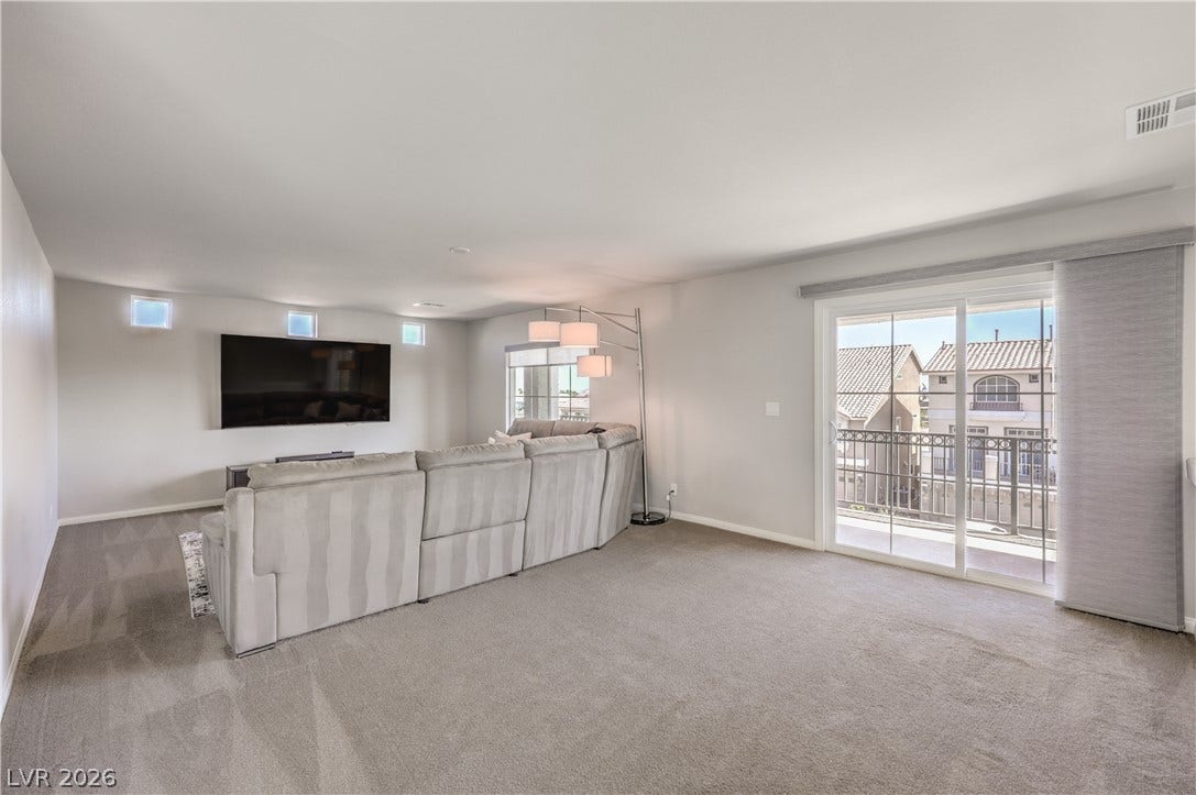 9267 Galen Glen Court, Las Vegas, NV 89139 Sliding glass doors open to a private balcony, filling the carpeted space with natural light.