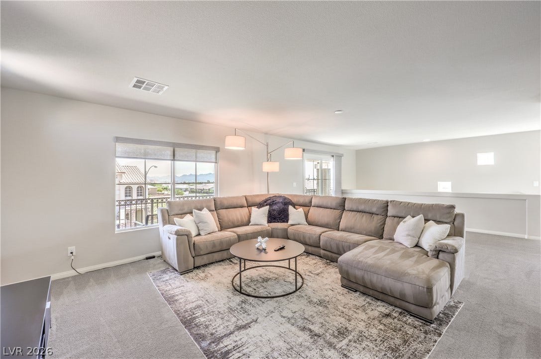 9267 Galen Glen Court, Las Vegas, NV 89139 An open upstairs loft area with soft carpet, high ceilings, and sliding doors to a balcony.