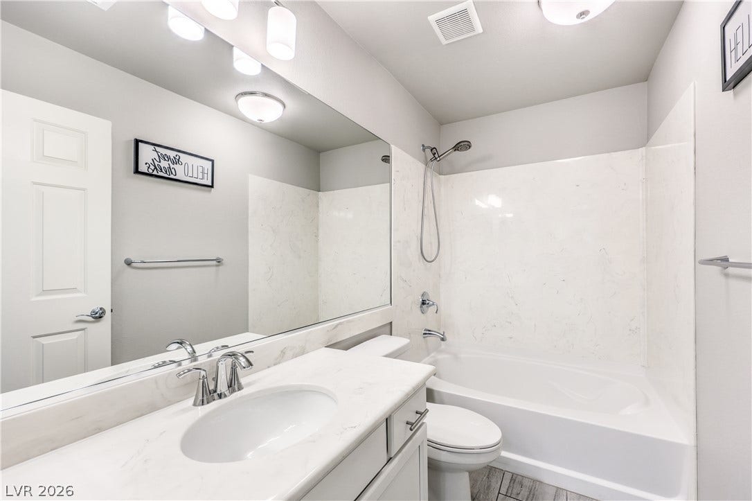 9267 Galen Glen Court, Las Vegas, NV 89139 A classic tub and shower combination sits adjacent to a white vanity with quartz stone counters.