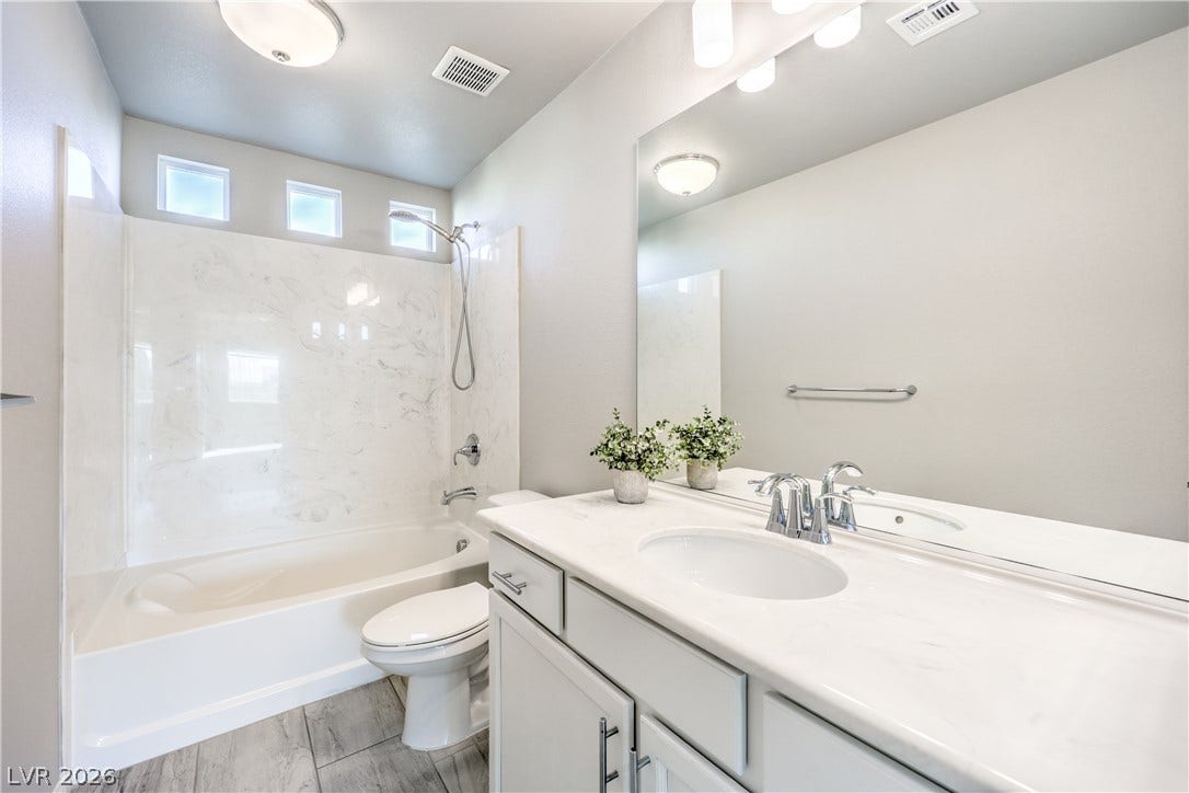 9267 Galen Glen Court, Las Vegas, NV 89139 Clean lines and a spacious vanity define this modern bathroom with a tub-shower combination.