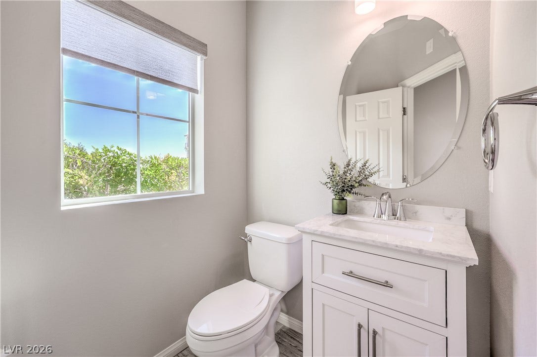 9267 Galen Glen Court, Las Vegas, NV 89139 A classic vanity with a stone counter sits beneath a large round mirror.