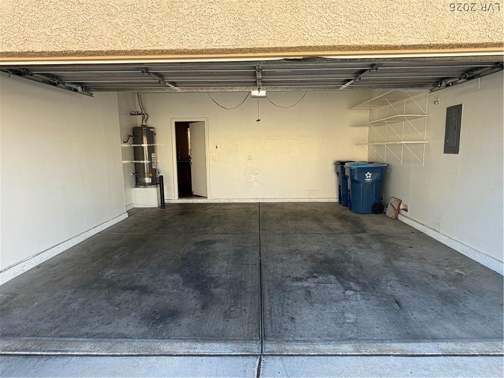 A spacious garage features durable concrete flooring, built-in shelving, and direct interior access.