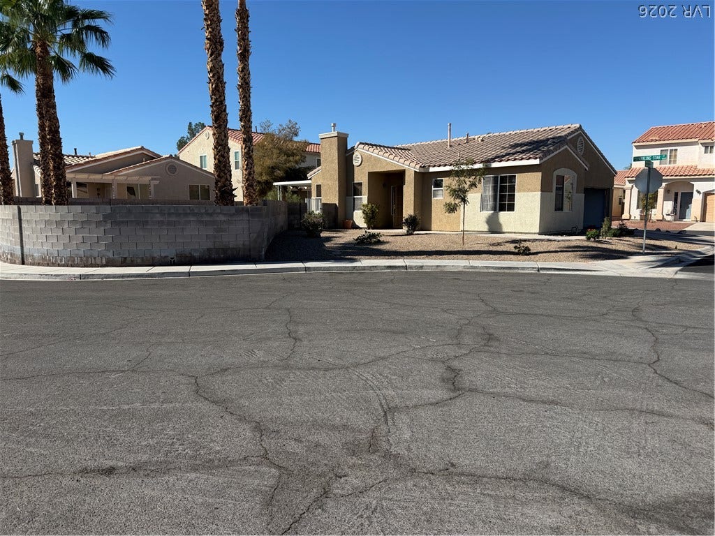 A classic stucco exterior is paired with a durable tile roof under clear blue skies.