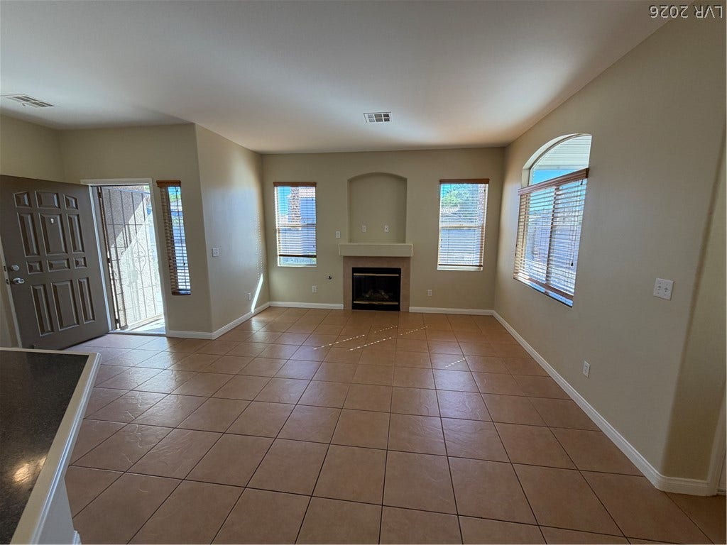 A tiled ceiling and integrated fireplace elevate this carpeted living room with multiple windows.