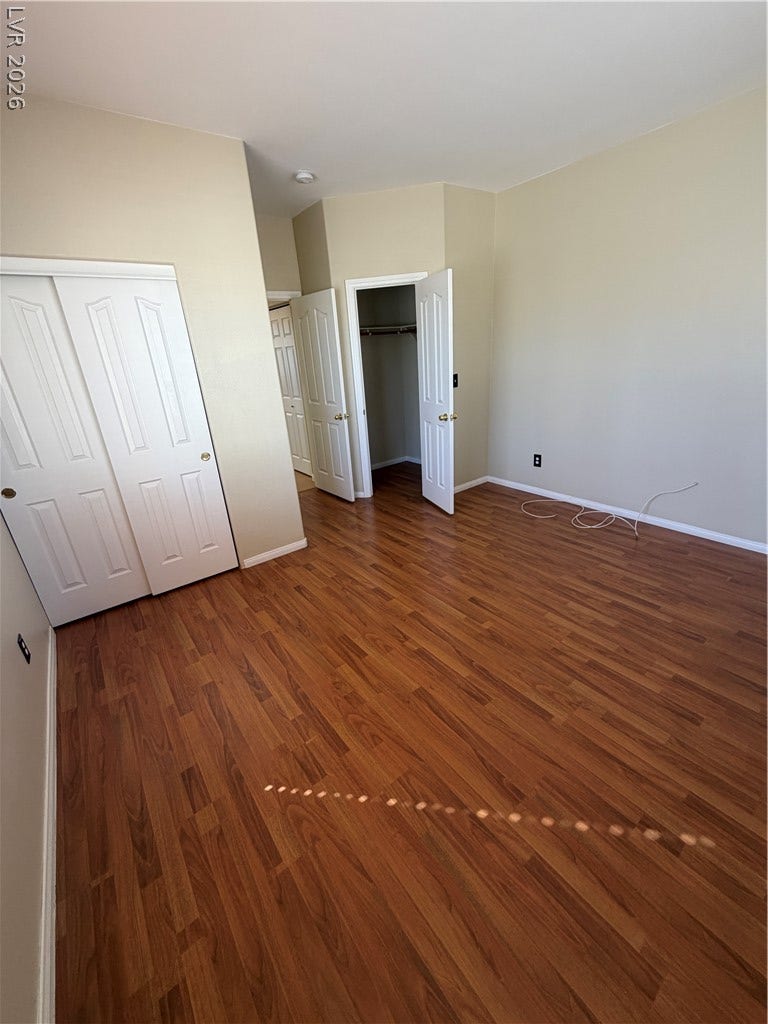 Gleaming wood flooring complements the neutral walls and dual closets in this versatile bedroom.