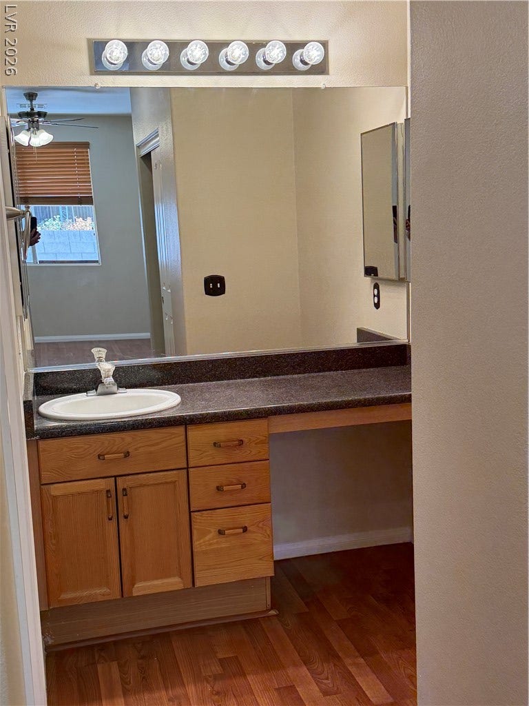 Rich wood cabinetry paired with dark stone counters defines this practical vanity area.
