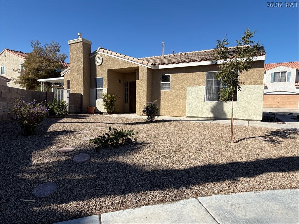 A classic stucco exterior features low-maintenance gravel landscaping under clear skies.