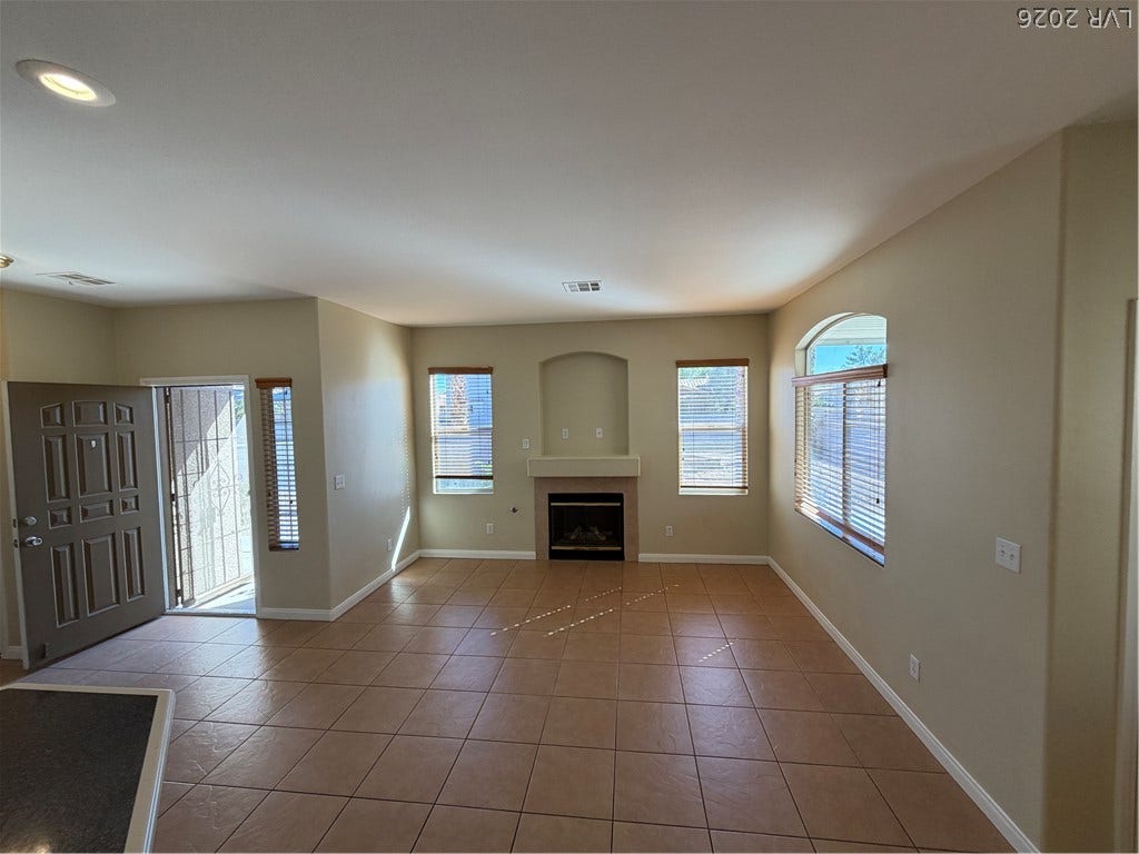 An inviting fireplace and a tiled ceiling accent this comfortable carpeted living space.