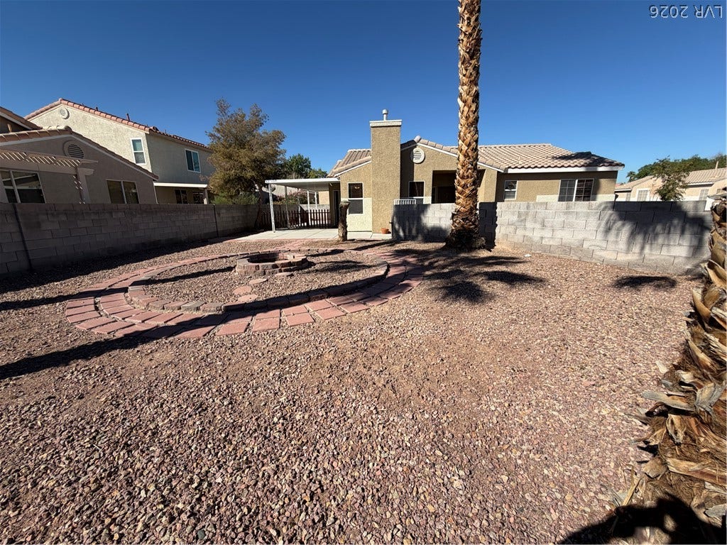 Low-maintenance desert landscaping frames a circular patio design in the enclosed backyard.