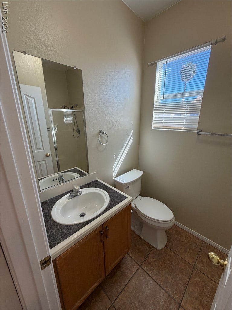 Tiled flooring and a wooden vanity define this classic secondary bathroom layout.