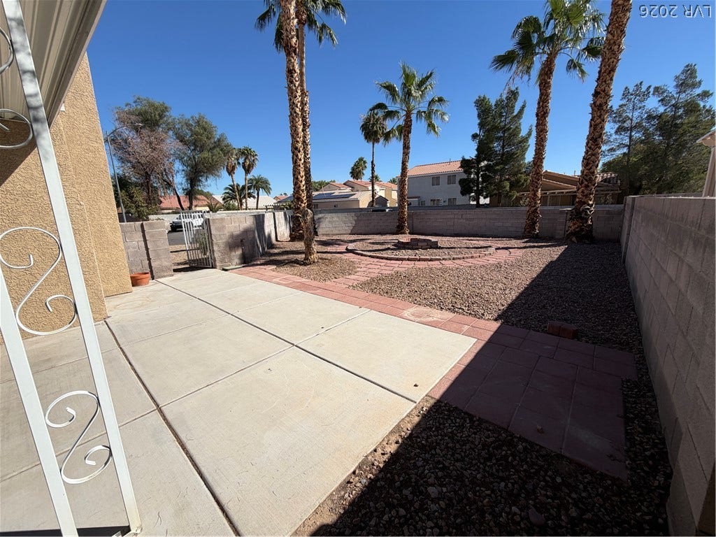Concrete patio spaces sit alongside low-maintenance gravel landscaping and mature palm trees.