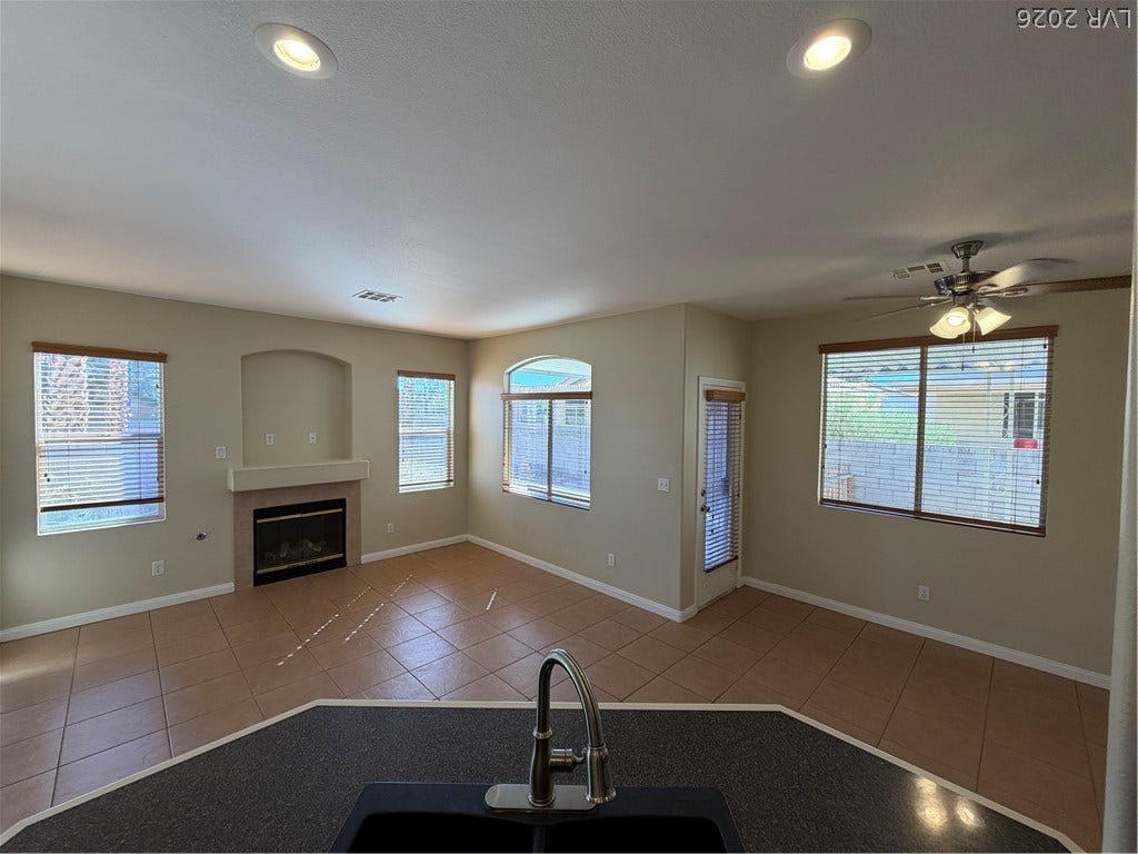 An overhead geometric ceiling and integrated fireplace anchor this sunlit, carpeted living area.