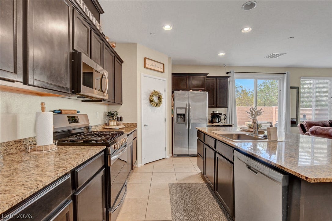 3924 Juanita May Avenue, North Las Vegas, NV 89032 Rich dark cabinetry and expansive granite countertops define this well-appointed modern kitchen space.