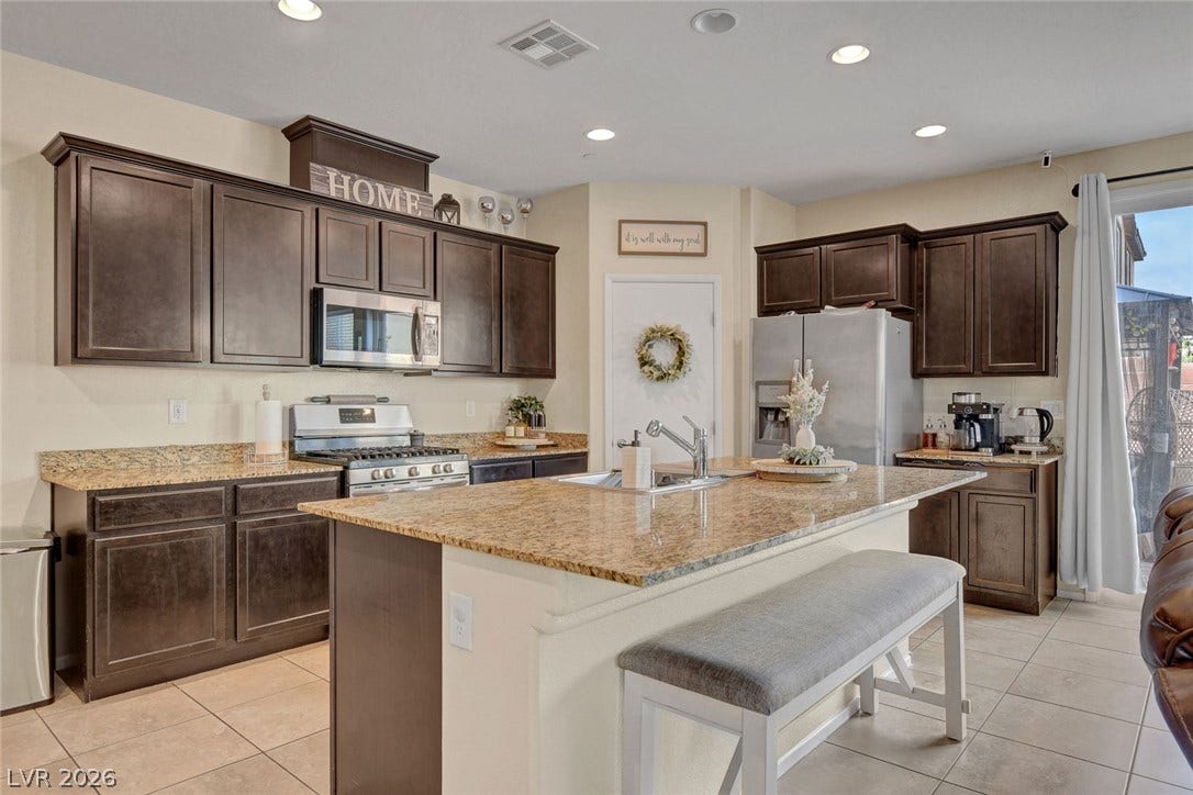 3924 Juanita May Avenue, North Las Vegas, NV 89032 Rich wood cabinetry paired with granite countertops anchors this functional kitchen layout.