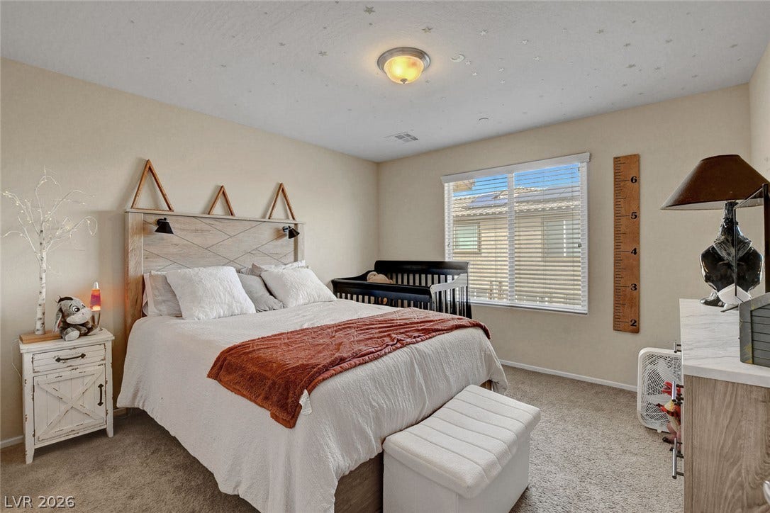 3924 Juanita May Avenue, North Las Vegas, NV 89032 Plentiful natural light streams through a large window into this cozy carpeted bedroom.