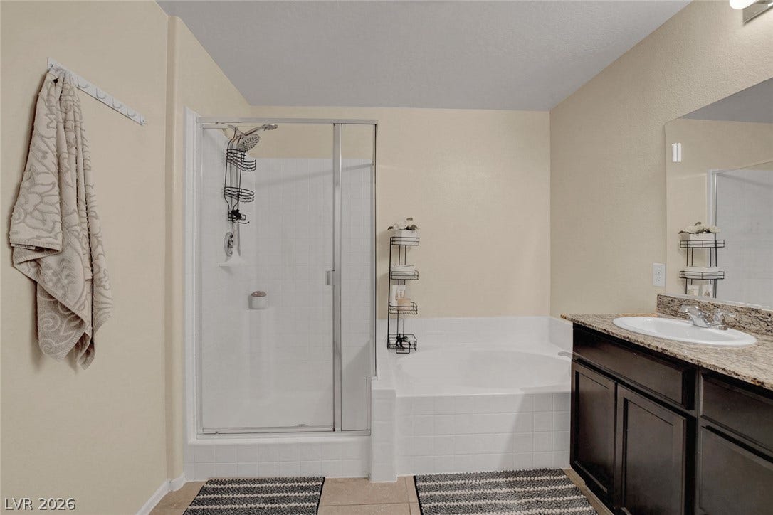 3924 Juanita May Avenue, North Las Vegas, NV 89032 A glass-enclosed walk-in shower stands alongside a soaking tub and stone-countertop vanity.