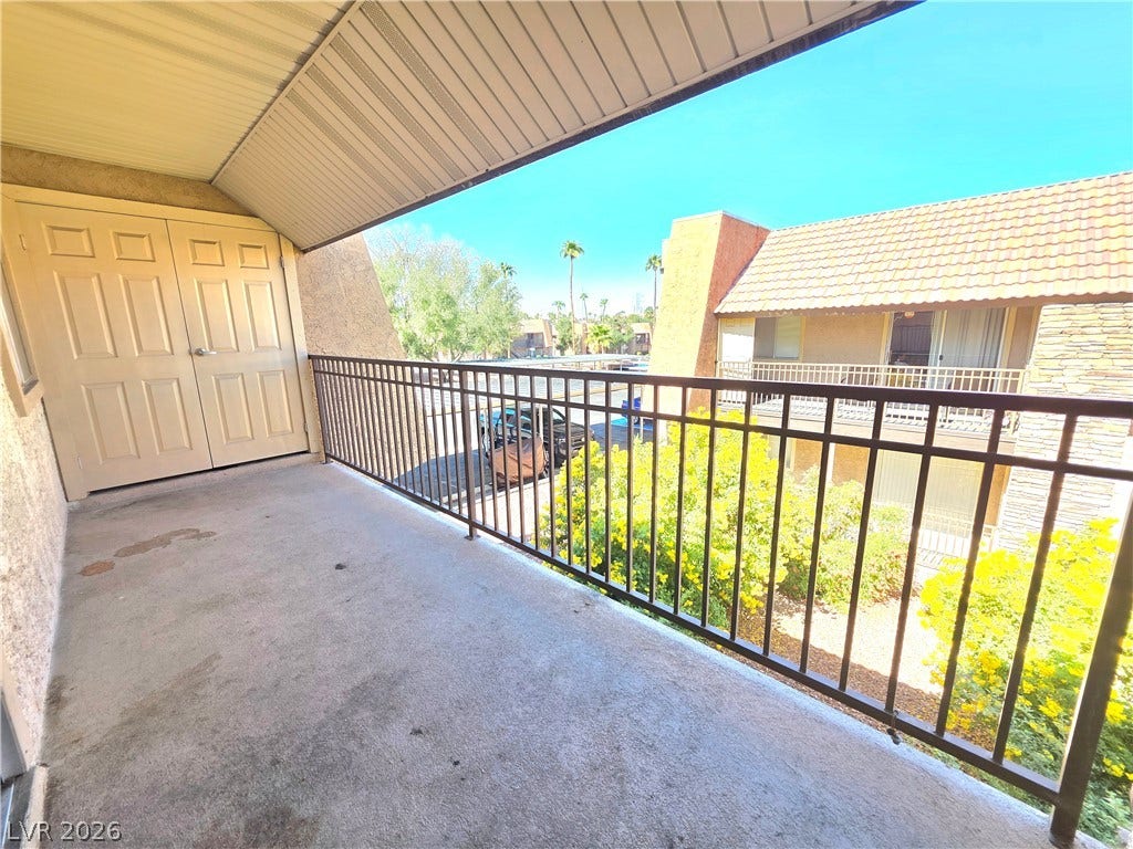 4470 Sandy River Drive, #54, Las Vegas, NV 89103 Shaded concrete balcony overlooks the community grounds under clear skies.