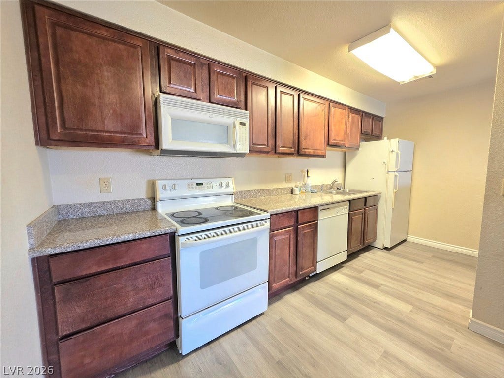 4470 Sandy River Drive, #54, Las Vegas, NV 89103 Rich wood cabinets and durable countertops line this functional workspace under clean overhead lighting.