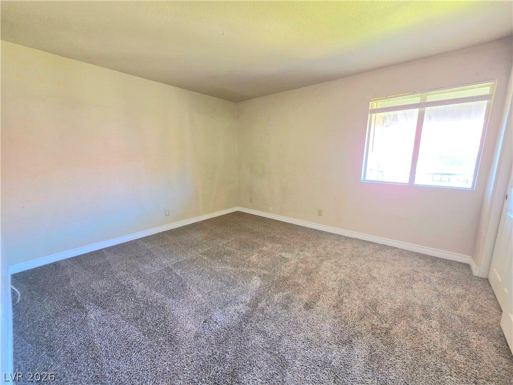 4470 Sandy River Drive, #54, Las Vegas, NV 89103 A spacious bedroom features plush carpeting and a large window inviting natural light.