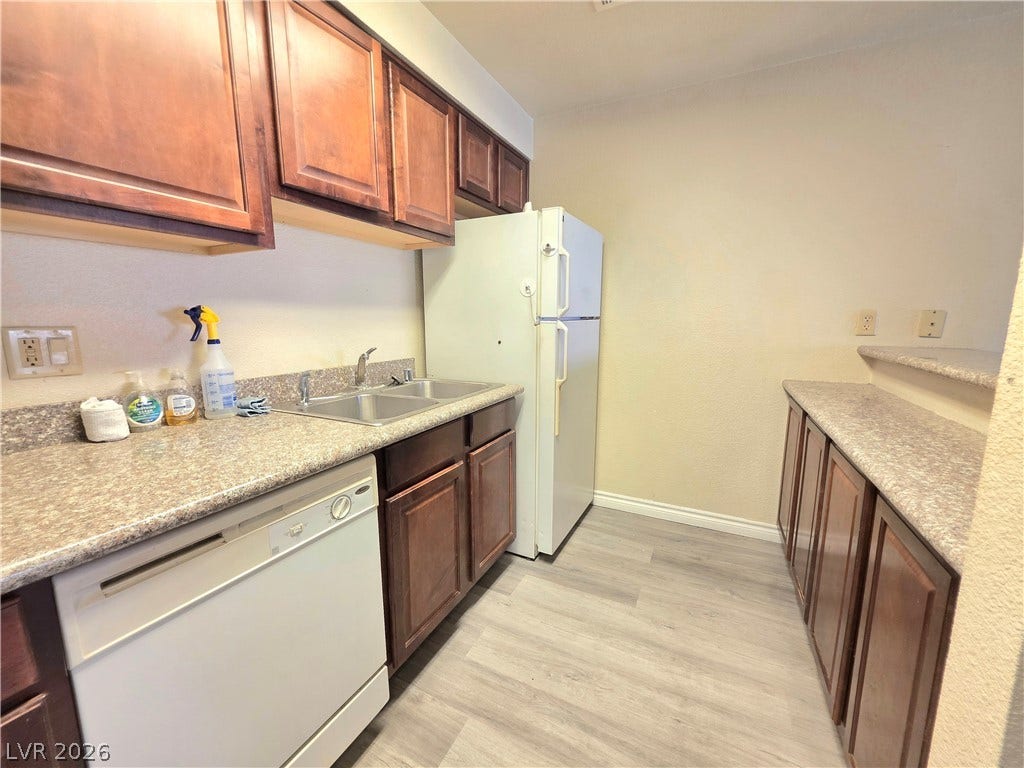 4470 Sandy River Drive, #54, Las Vegas, NV 89103 Warm wood cabinetry and durable vinyl flooring define this functional kitchen workspace.
