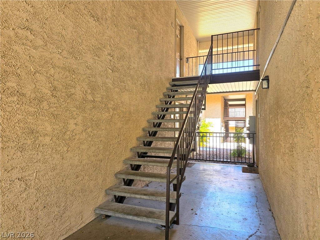 4470 Sandy River Drive, #54, Las Vegas, NV 89103 Stucco walls flank concrete stairs rising to an upper outdoor walkway with metal railings.