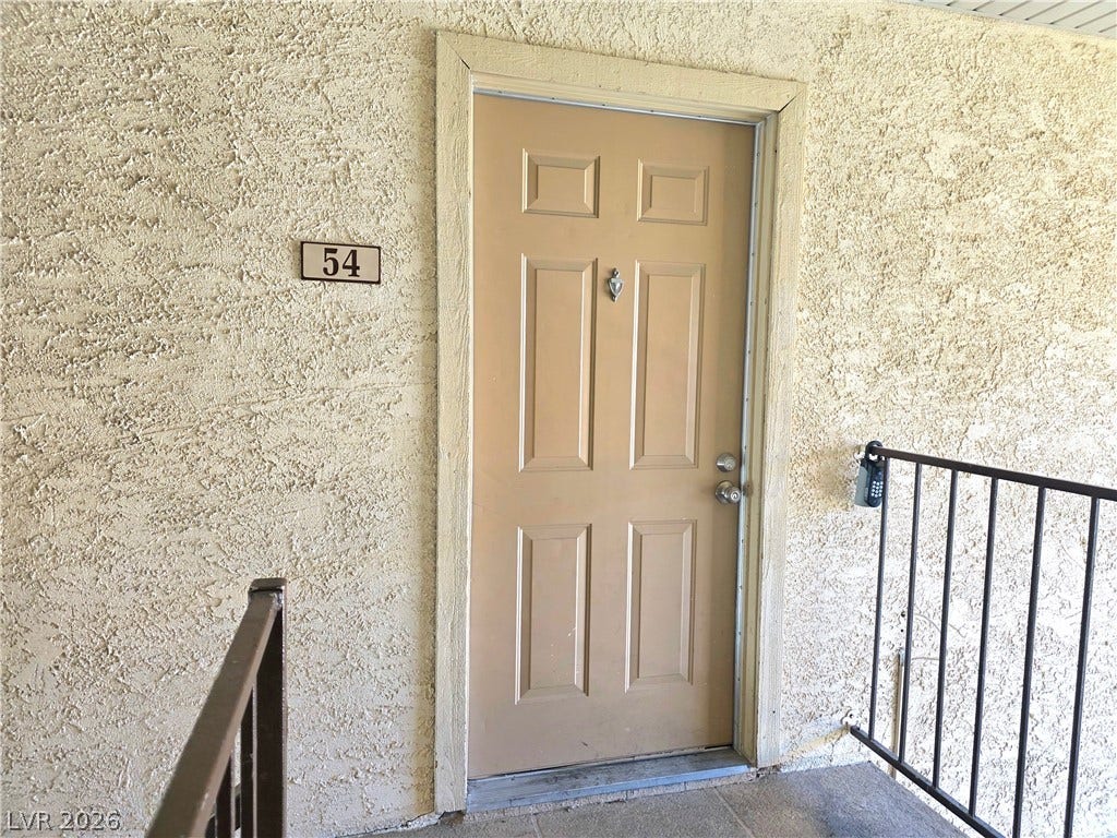 4470 Sandy River Drive, #54, Las Vegas, NV 89103 A classic paneled door and textured stucco walls define this welcoming residential entry.