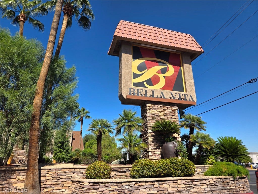 4470 Sandy River Drive, #54, Las Vegas, NV 89103 Towering palm trees frame the stone-accented community sign against a clear blue sky.