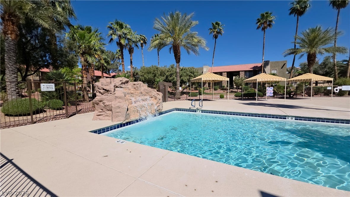 4470 Sandy River Drive, #54, Las Vegas, NV 89103 Palm trees surround a clear swimming pool featuring a rock waterfall feature.
