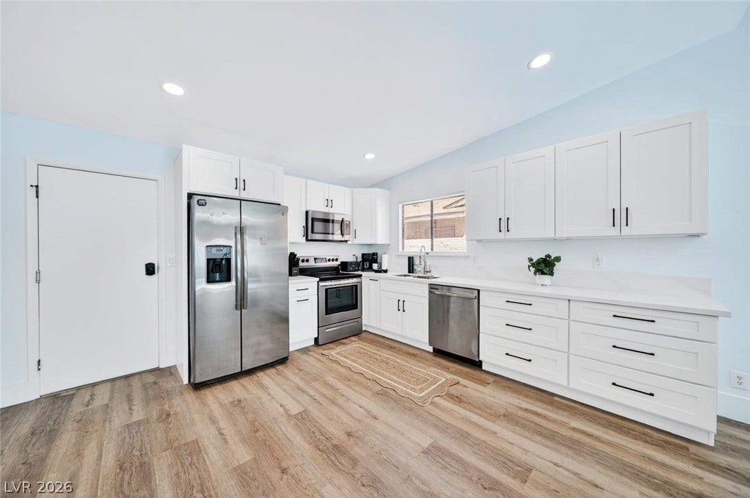 6191 Bullion Boulevard, Las Vegas, NV 89103 Warm wood-toned floors and white cabinetry define this bright, open kitchen space.