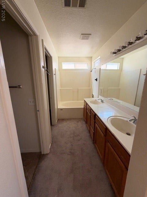 2506 Lady Elizabeth Court, North Las Vegas, NV 89031 A spacious vanity area with built-in wooden cabinetry seamlessly transitions into the private bathing quarters.