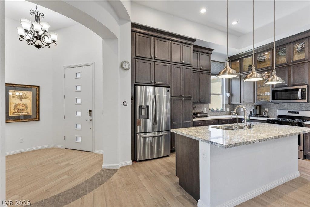 6722 Desert Crimson Street, Las Vegas, NV 89148 High ceilings and arched openings connect the tiled foyer to a modern kitchen.